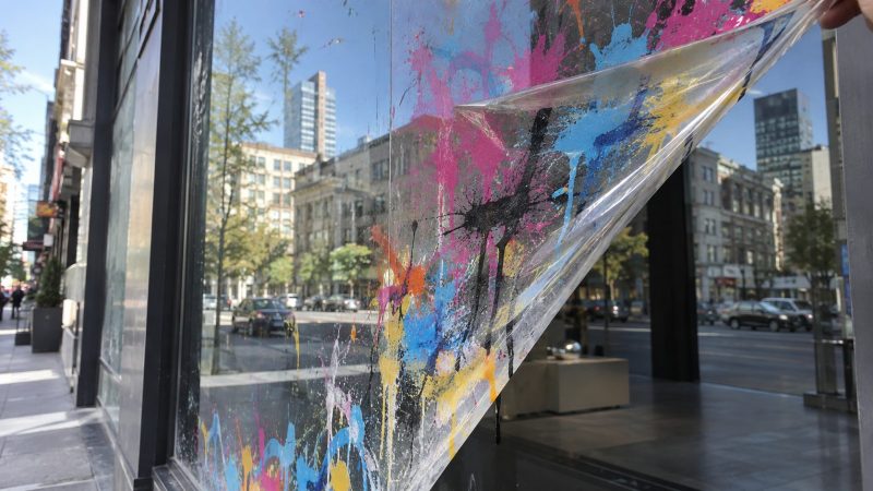 Schaufensterscheibe, von der eine besprühte Anti-Graffiti-Folie abgezogen wird