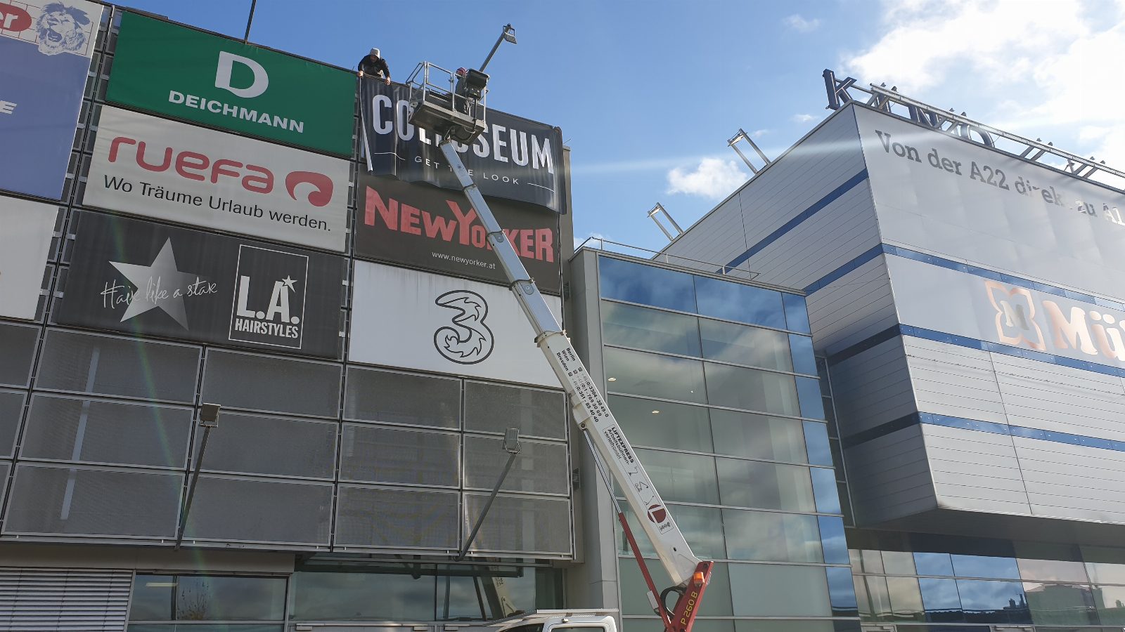 Montage eines Großformatbanners an Einkaufszentrum mit Hubsteiger – AbdeX Werbetechnik